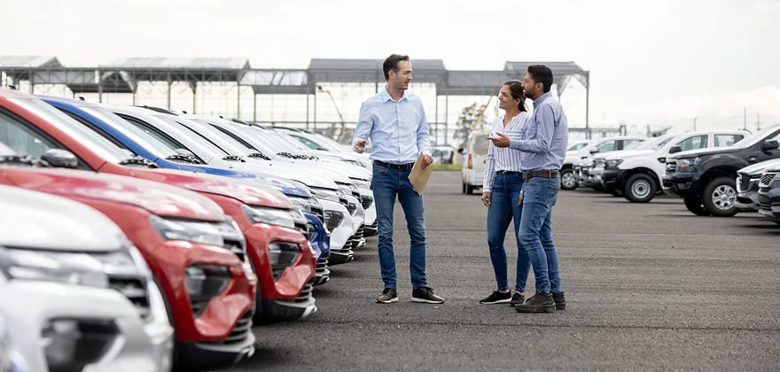 a couple looks at cars at a dealership