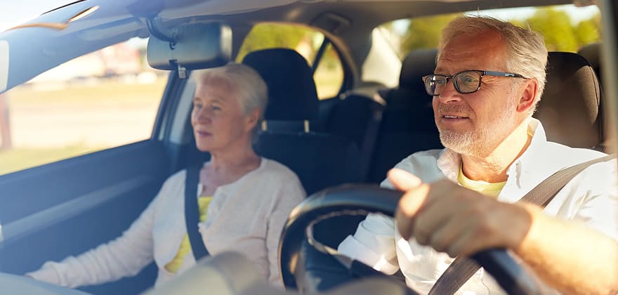 two mature drivers in a car driving