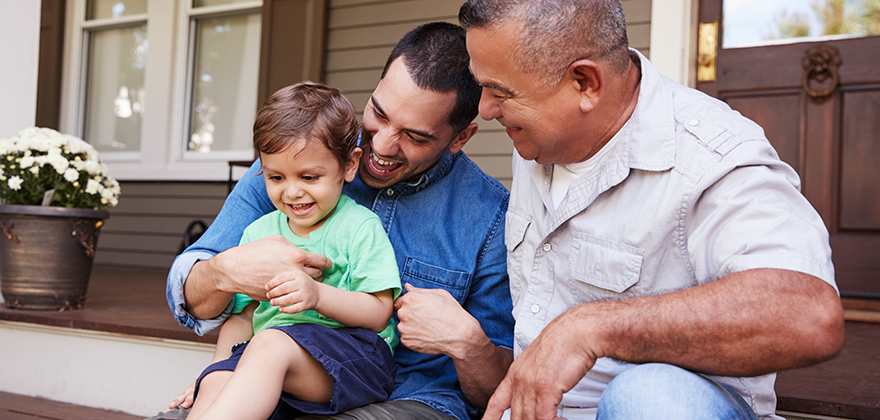 two men sitting outside with kid