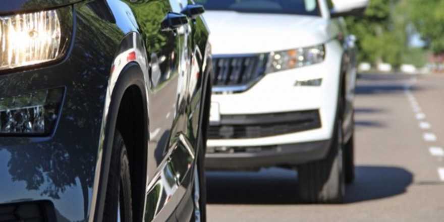 a close-up of two cars driving on a suburban road