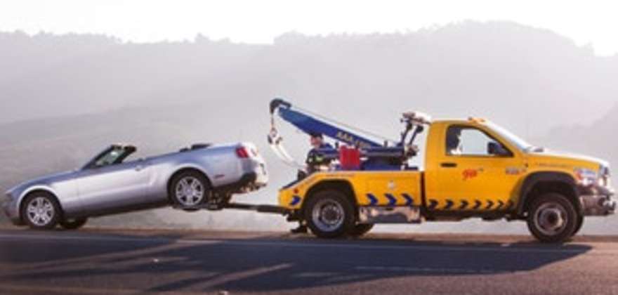 A AAA tow truck assists a car stranded on the side of the road.