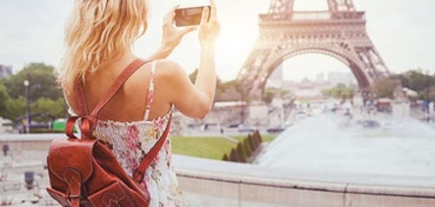 woman on vacation in paris takes picture of eiffel tower with her camera