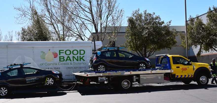 a flatbed AAA tow truck hauls a GIG car