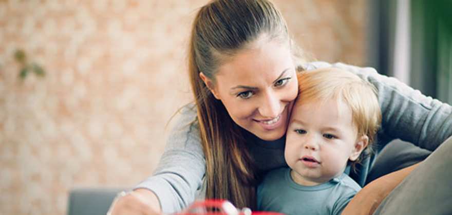 a mom with AAA life insurance plays on the couch with her toddler son