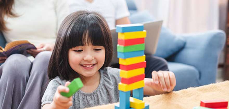 a girl plays with legos in her house insured with AAA