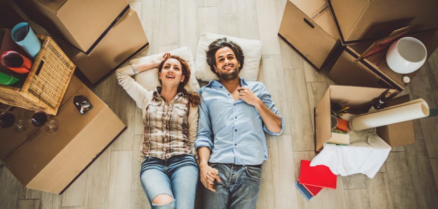 a couple with aaa membership rests on the floor of their new home after moving with aaa discounts