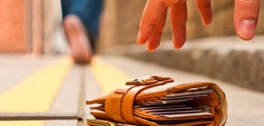 a person picks up a wallet from the ground