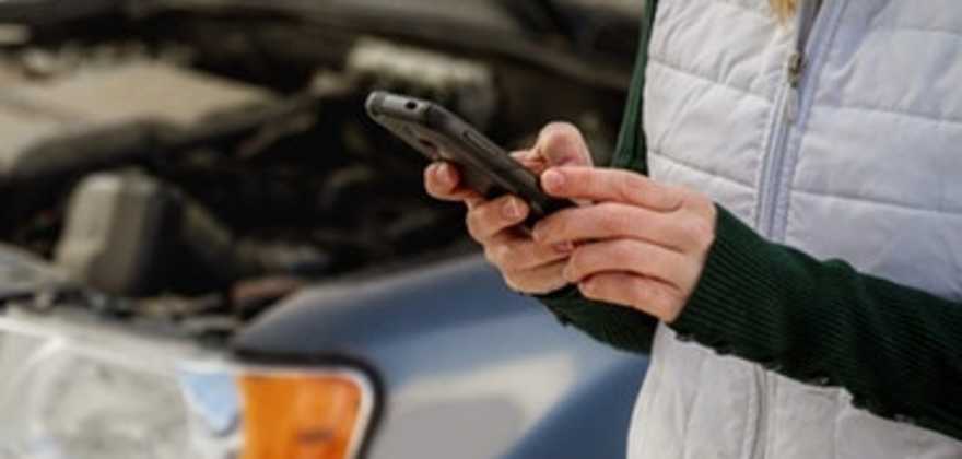 A woman uses the AAA app to request AAA Roadside assistance