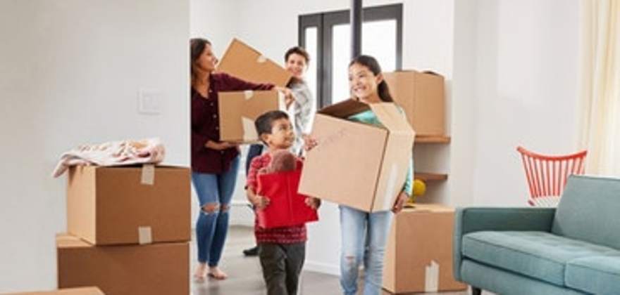 family of four carrying moving boxes into their new home covered by AAA homeowners insurance