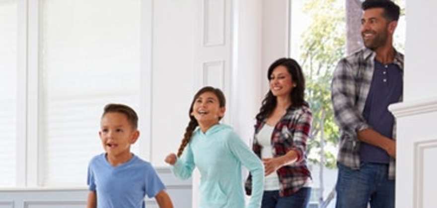 mother, father and two children walking through the front door of their home covered by aaa homeowners insurance