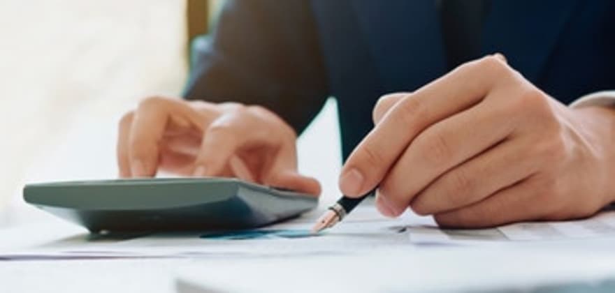 business person using a calculator to determine closing costs on a new home