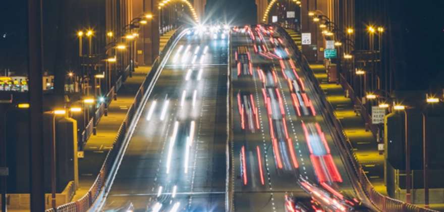 Cars driving at night over a bridge with white and red lights blurred