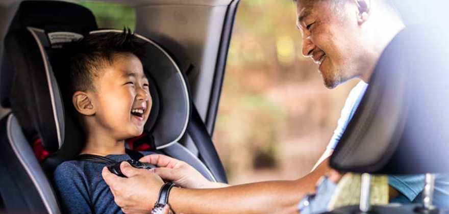 A parent harnesses a child in a car seat