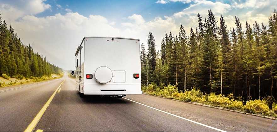 Motorhome RV covered by AAA Insurance driving through trees