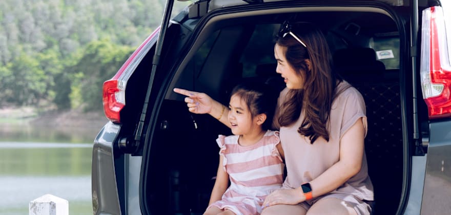 AAA Member and a child sit in the back of the car looking at a lake