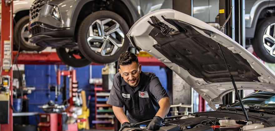 Technician performing work under the hood of car