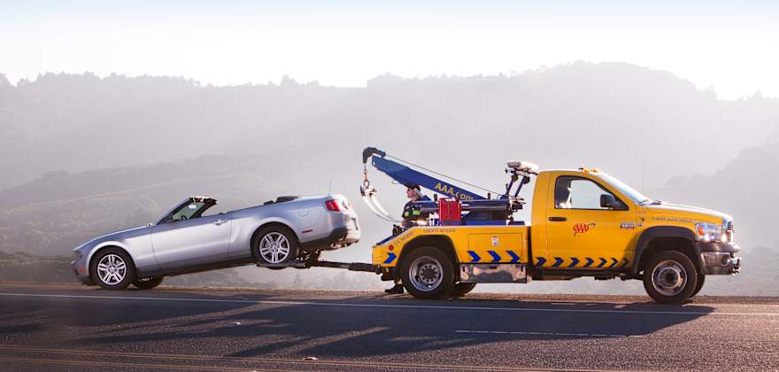 A AAA tow truck assists a car stranded on the side of the road.