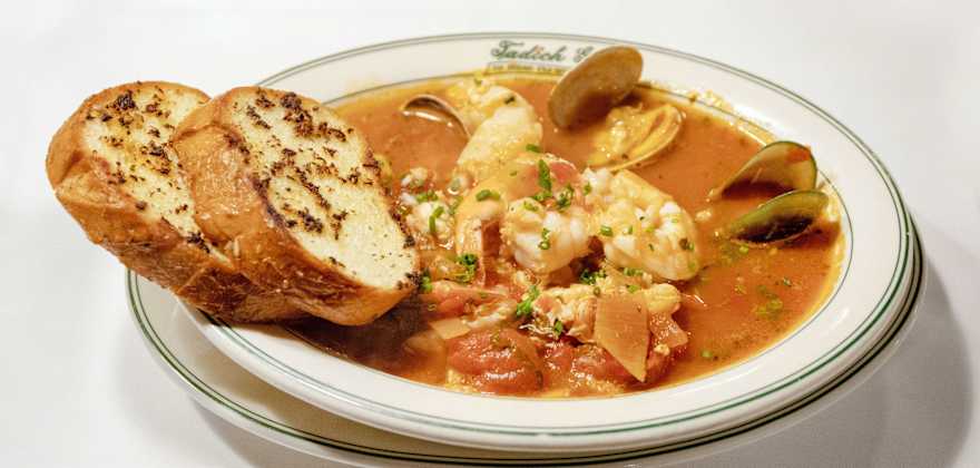 A bowl of cioppino, or seafood in a tomato broth, served with crusty bread at Tadich Grill. 