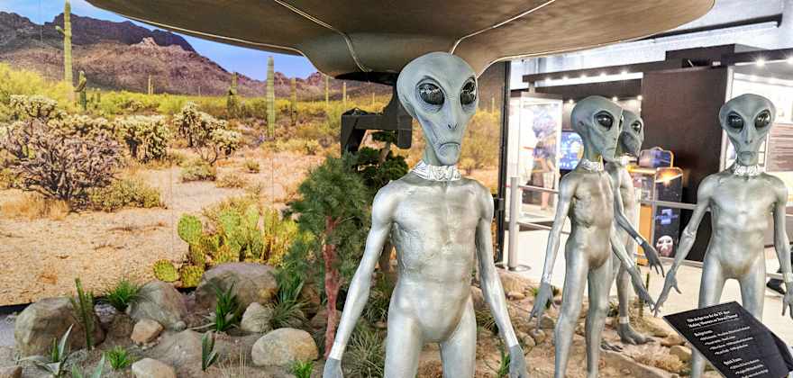 Alien figures stand before a UFO in a museum exhibit