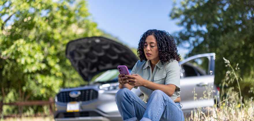 person looks at their phone comparing roadside plans