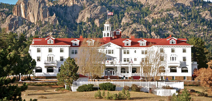 The Georgian revival Stanley Hotel with the Rocky Mountains behind it.