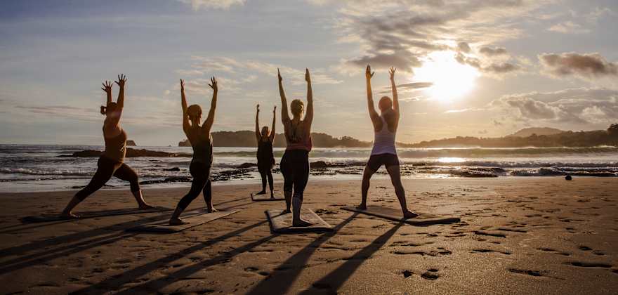 people doing yoga on a beach