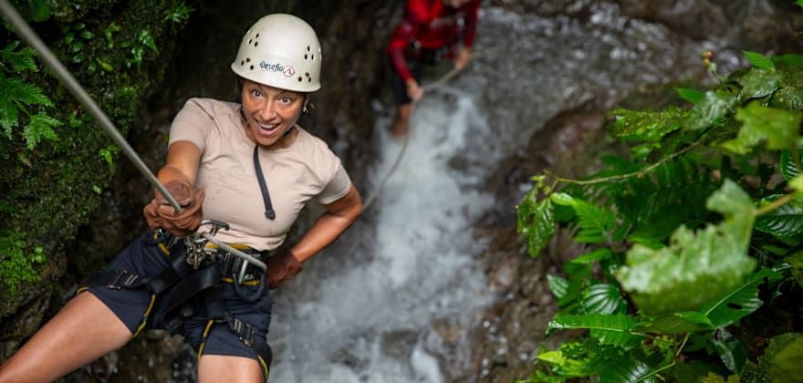 woman rappelling down cliff