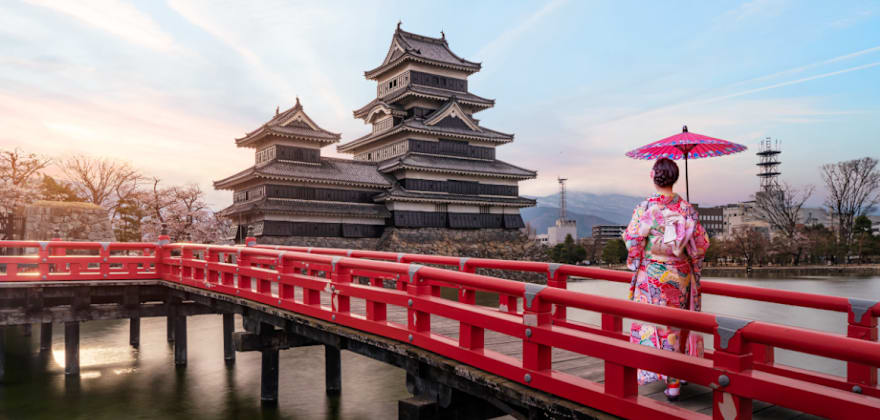 woman walking on bridge in front of japanese castle