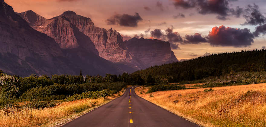 Beautiful View of Scenic Highway with American Rocky Mountain Landscape in the background. Colorful Summer Sunrise Sky. Taken in St Mary, Montana