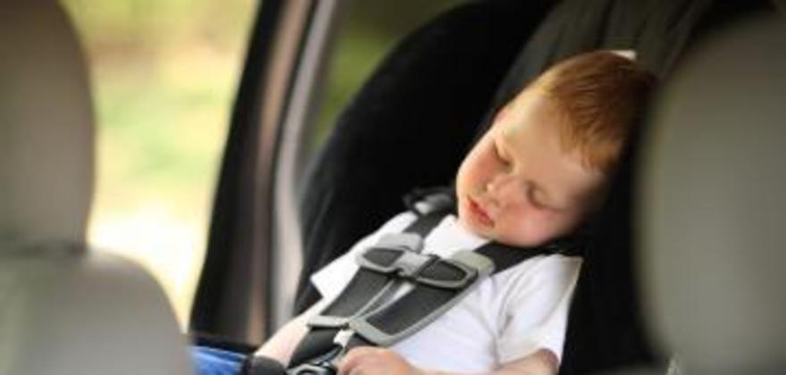 boy sleeps in booster car seat inspected by AAA technician