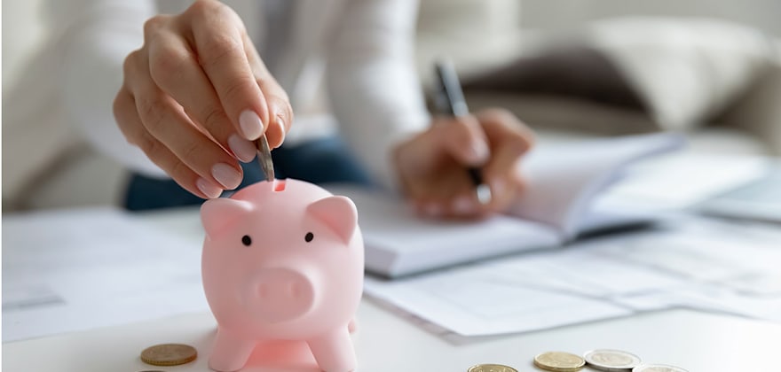 A woman with AAA Auto Insurance puts her savings in a piggy bank
