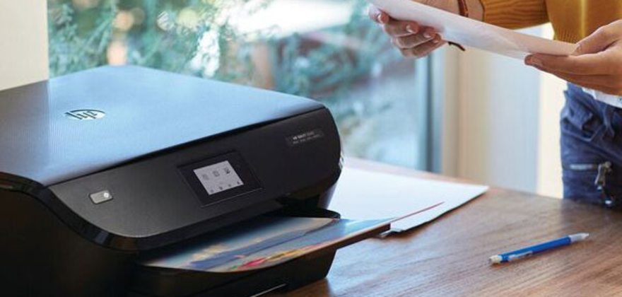 AAA member standing next to an HP printer on a desk
