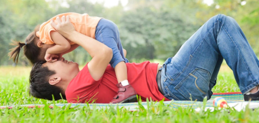 Father with AAA life insurance plays with his toddler daughter in a park