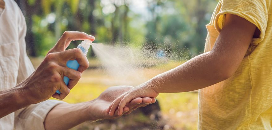 Adult applies bug spray to a child.