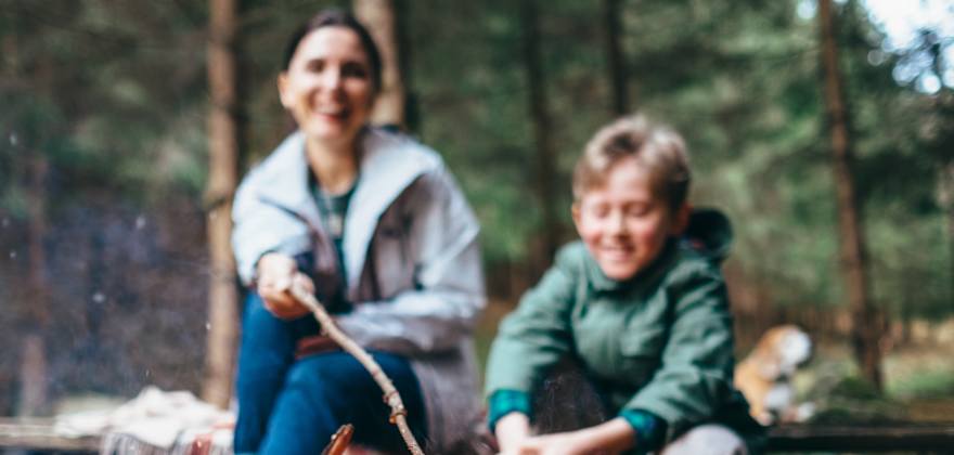 Mother and son roast marshmallows over the campfire.
