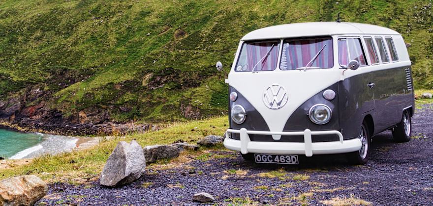 Volkswagen bus van parked next to ocean.