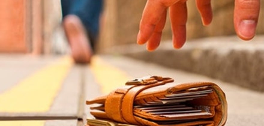 a person picks up a wallet from the ground