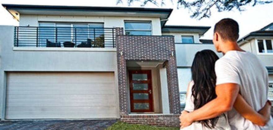 a couple stands in front of their new home  with AAA homeowners and earthquake insurance 