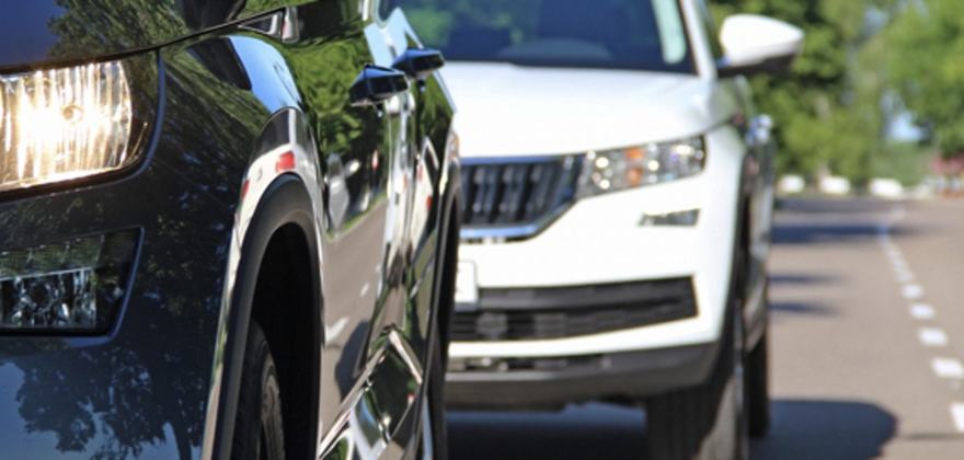a close-up of two cars driving on a suburban road