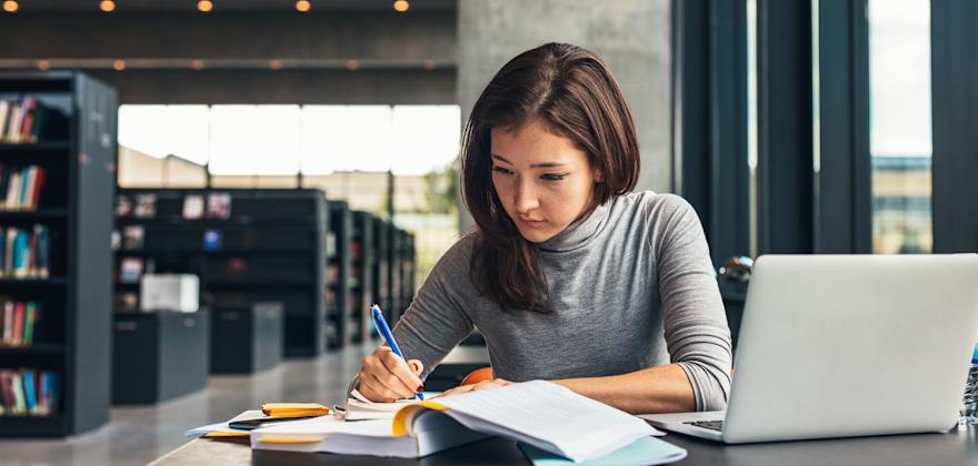 A college student does homework in the library on campus.