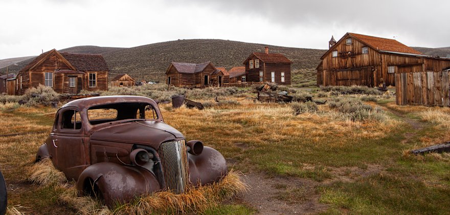 Rusted car and abandoned buildings in the ghost town of Bodie, California.