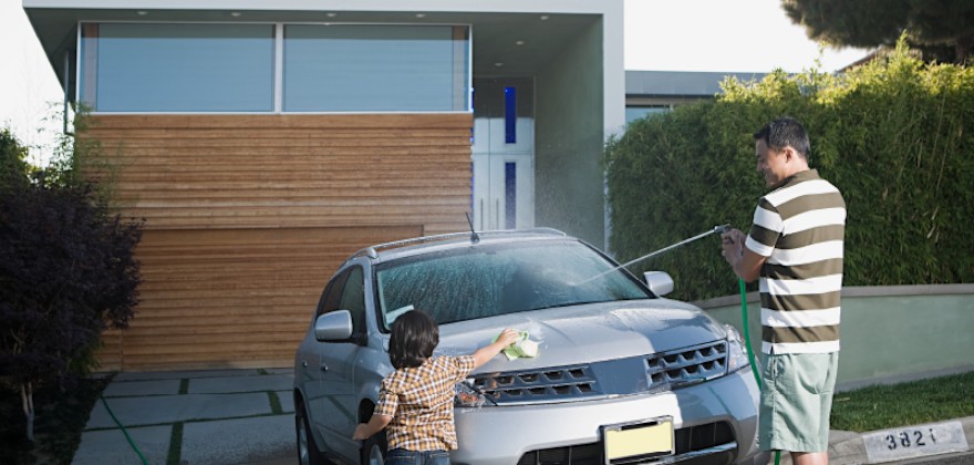 Father and son washing car in driveway