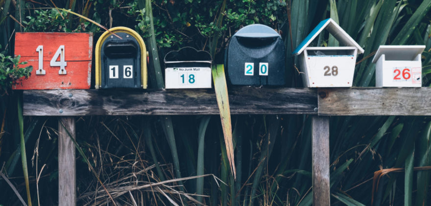 A row of mailboxes are lined up on a wooden post