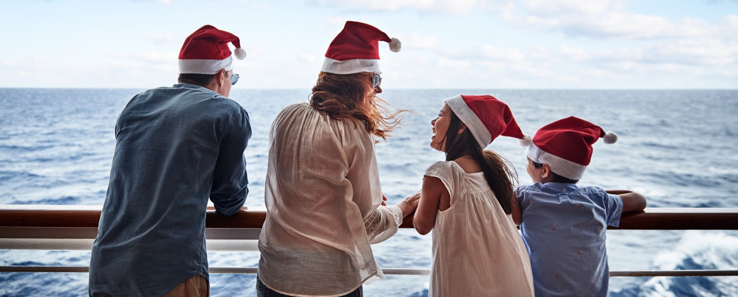 family wearing santa hats on deck of ship on holiday cruise