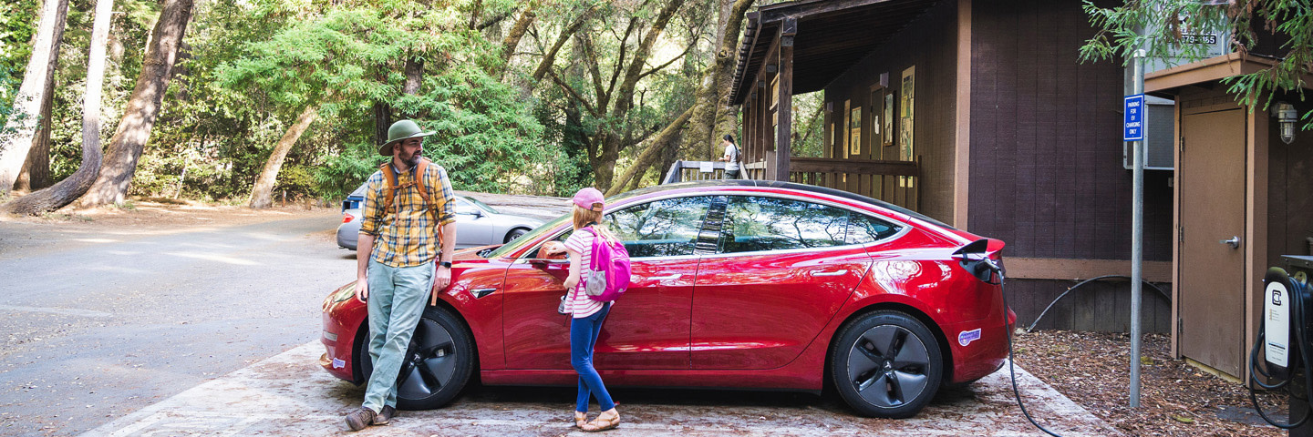 Father and daughter standing next to tesla