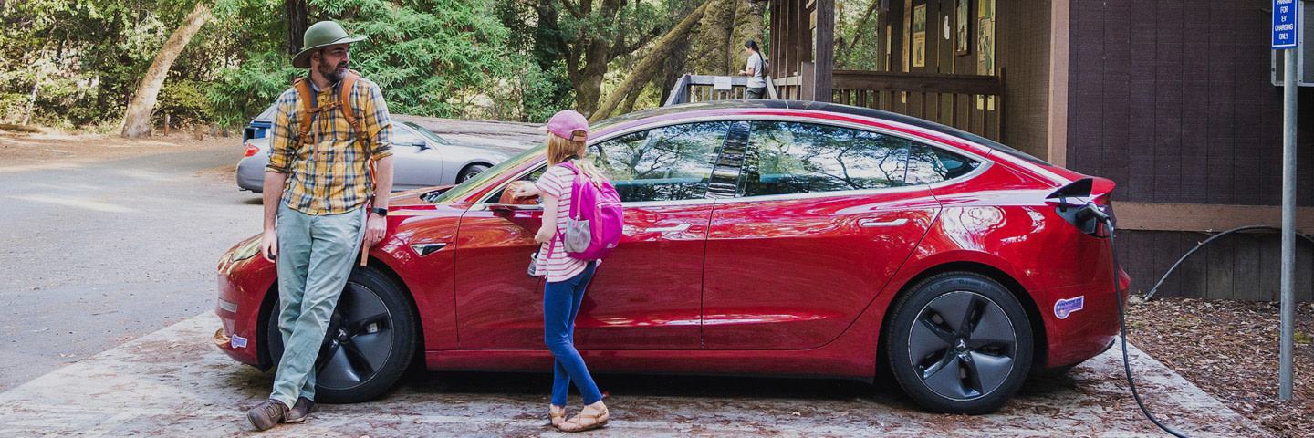 Father and daughter standing next to tesla