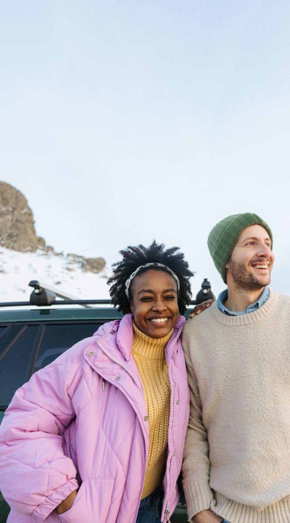 Man and woman sitting on car and watching sunset