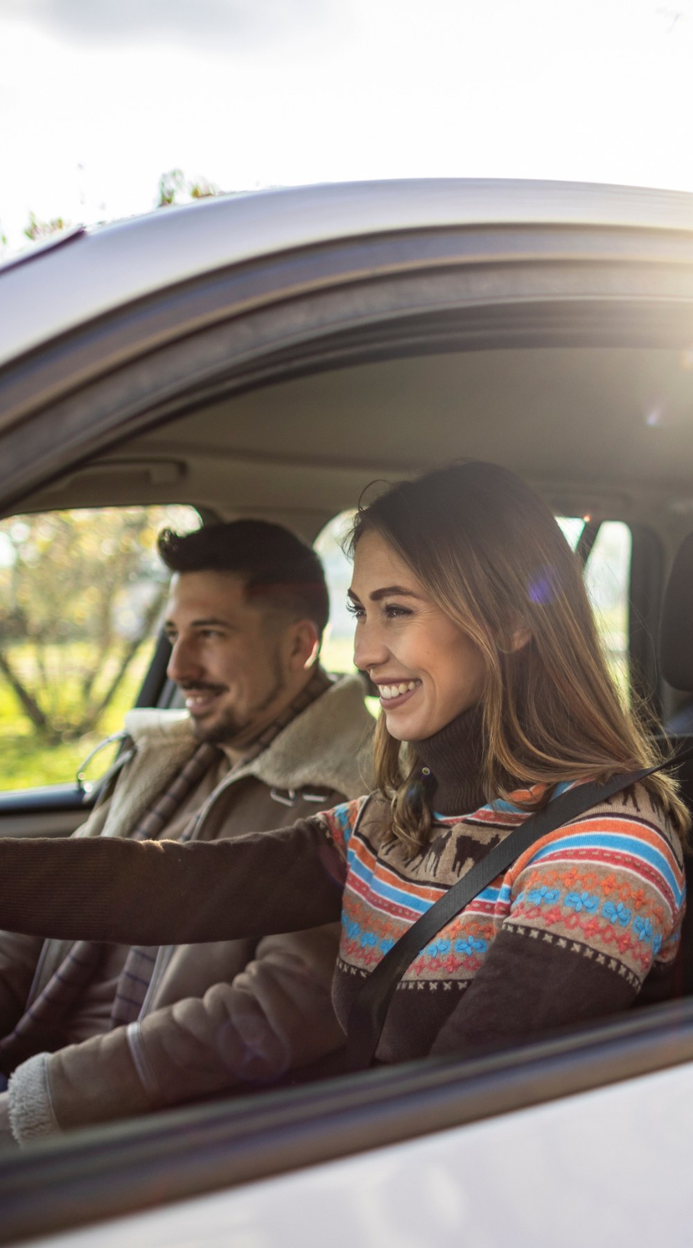 Man and woman sitting on car and watching sunset