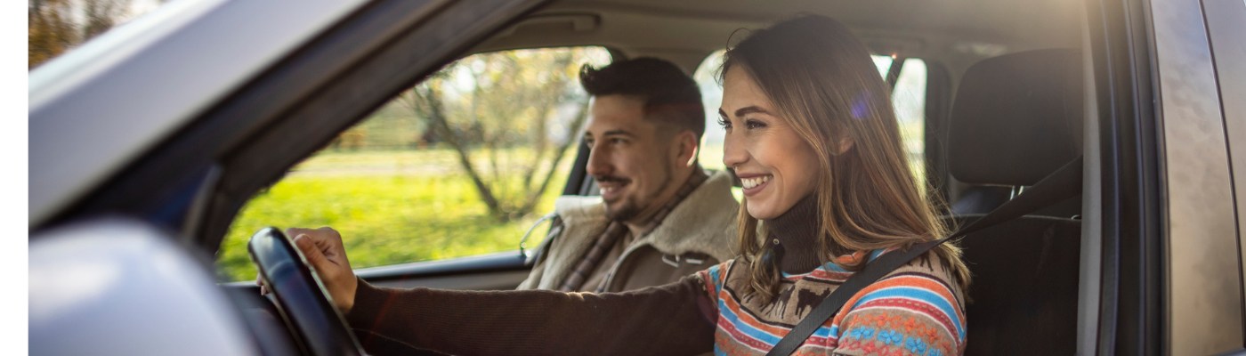 Man and woman sitting on car and watching sunset
