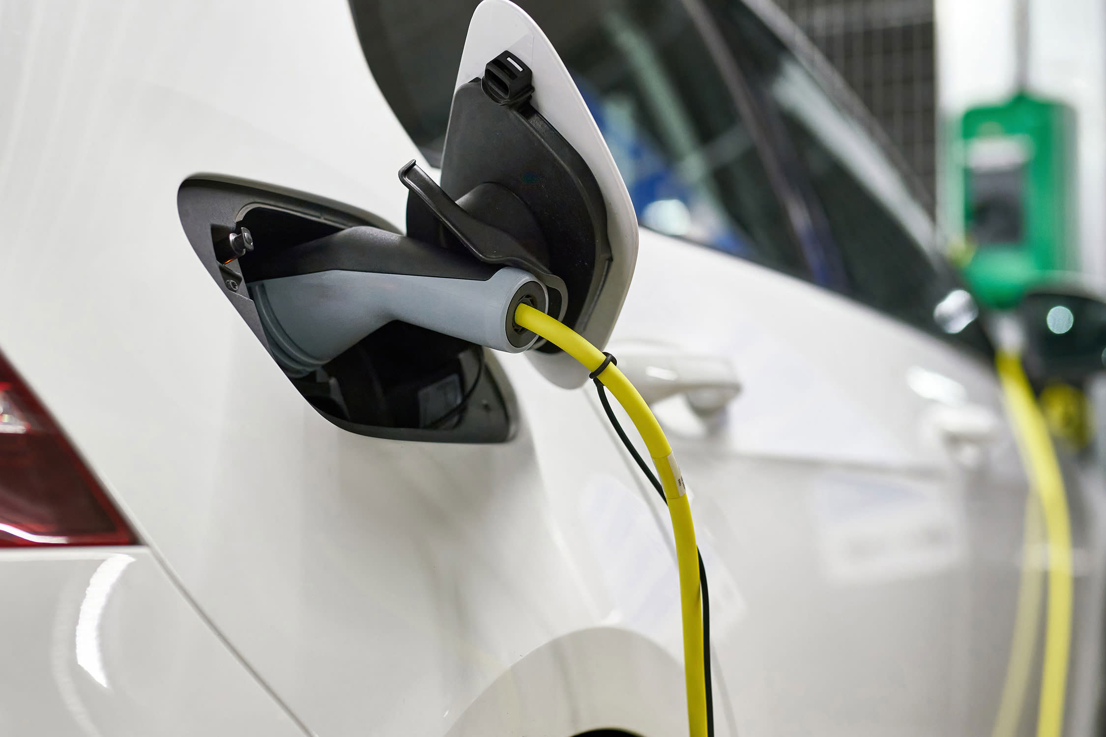 A white EV plugged in to charge.